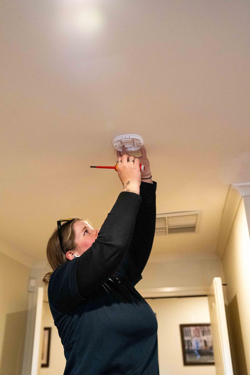 Electrician installing a compliant smoke alarm