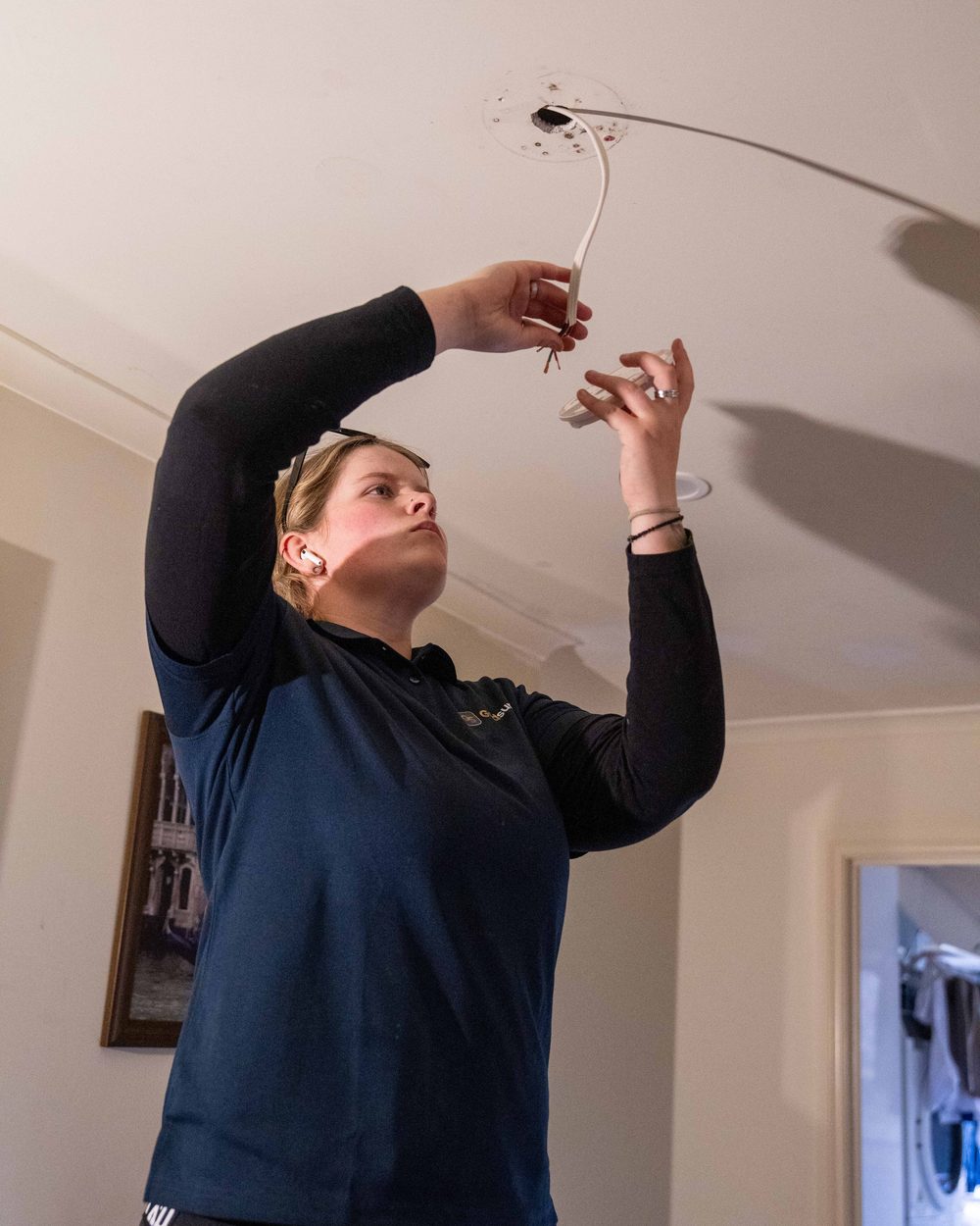 A licensed Goldsure electrician installing a compliant smoke alarm in a Queensland home