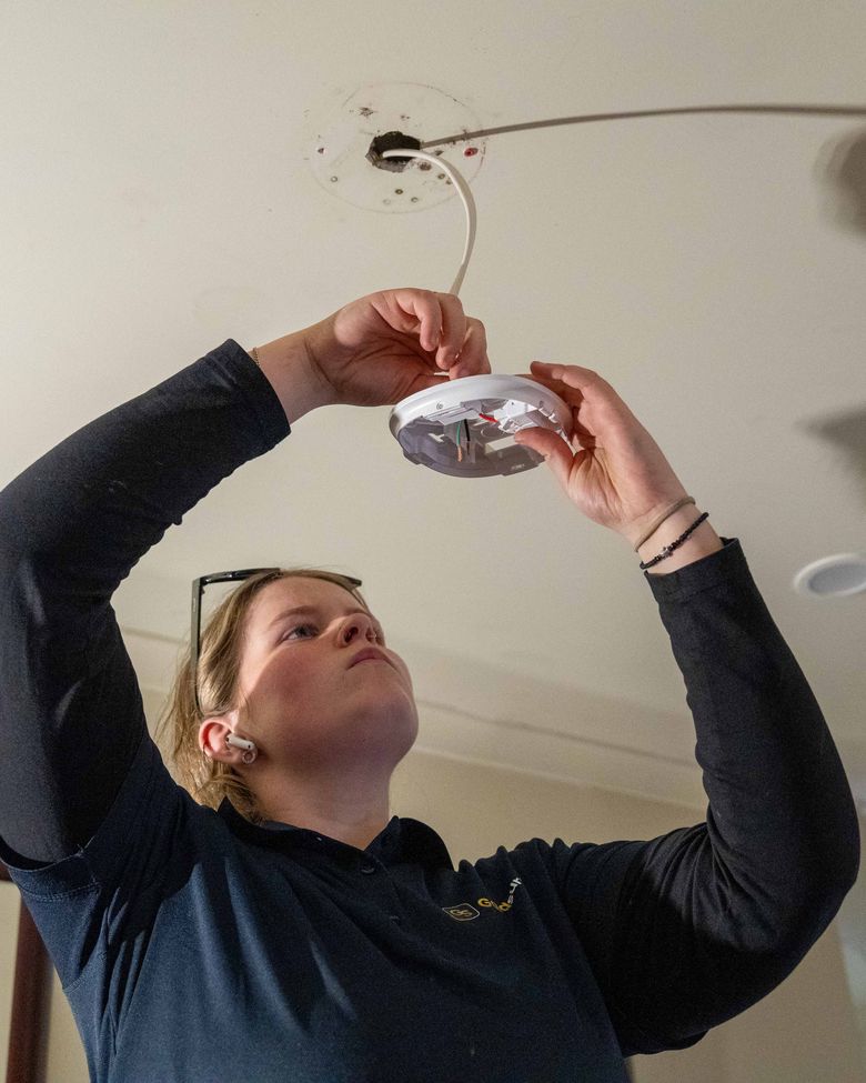 Goldsure electrician installing a smoke alarm at a Brisbane home